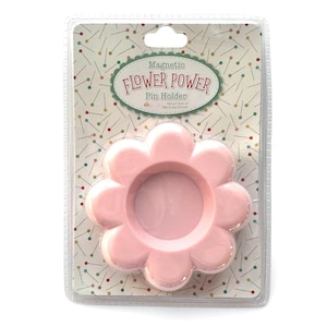 Könnte beinhalten: Ein rosa, blütenförmiger magnetischer Nadelhalter in einer transparenten Kunststoffverpackung. Der Nadelhalter hat einen zentralen kreisförmigen Bereich und blütenblattförmige Kanten. Die Verpackung trägt den Text "Magnetic Flower Power Pin Holder."