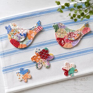 May include: Two quilted fabric bird ornaments and three quilted fabric flower ornaments, all crafted from various colorful patterned cotton scraps featuring floral, plaid, and polka dot designs in shades of red, orange, blue, green, and purple.