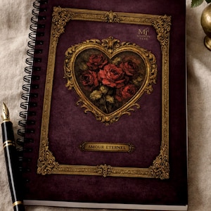 Puede incluir: Un cuaderno con espiral con una cubierta morada oscura que presenta un corazón enmarcado en oro lleno de rosas rojas. La cubierta también tiene el texto "AMOUR ETERNEL" y "MI MAISON TUTE". Una pluma estilográfica negra descansa junto al cuaderno.