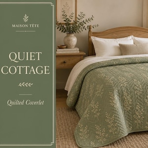 May include: A sage green quilted coverlet featuring a white botanical sprig pattern and a chevron stitch design. The coverlet is draped over a bed with white pillows and a tan accent pillow, with text reading MAISON TETE QUIET COTTAGE.