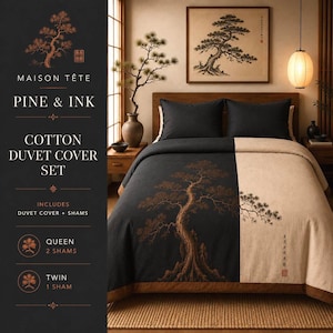 May include: A cotton duvet cover set by Maison Tête titled Pine & Ink. The set features a two-tone design with a black side displaying a large brown pine tree graphic and a beige side. Includes two dark pillow shams and a matching duvet cover.
