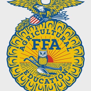 Op de afbeelding: Een cirkelvormig FFA-embleem met een geel en blauw ontwerp. Het embleem toont een adelaar, een schild met sterren en strepen, en de woorden "AGRICULTURAL EDUCATION" en "FFA". Een uil en een ploeg zijn ook inbegrepen.