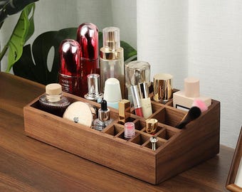 May include: A wooden makeup organizer with multiple compartments, filled with various cosmetic products. The organizer is made of dark brown wood and sits on a wooden surface. The cosmetics include bottles, lipsticks, and brushes.