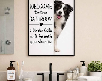 Peut inclure: Un panneau de salle de bain encadré avec le texte "WELCOME to the BATHROOM" et "a Border Collie will be with you shortly." Un chien Border Collie noir et blanc apparaît derrière le panneau. Le panneau est au-dessus d'un lavabo.