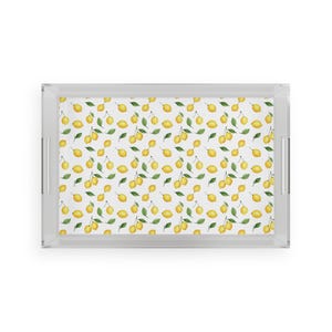 May include: A rectangular serving tray with a clear acrylic frame and handles. The tray's surface features a repeating pattern of yellow lemons and green leaves on a white background. The tray is designed for serving food and drinks.