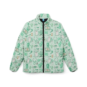 Peut inclure: Une veste bouffante vert clair avec une fermeture éclair et un col noirs. La veste est recouverte d'un motif répété de fournitures médicales, notamment des stéthoscopes, des seringues et des gants. Thème médical.