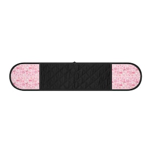 May include: A black quilted double oven mitt with pink patterned ends. The pink pattern features small illustrations of kitchen items. The mitt has a loop for hanging and is designed to protect hands from heat.