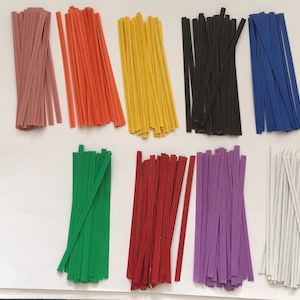 May include: A collection of colorful paper strips in various shades, including pink, orange, yellow, black, blue, green, red, purple, and white. The strips are arranged in neat piles, offering a vibrant display of craft supplies.