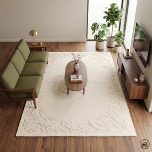 Puede incluir: Un salón con una alfombra crema con borde floral, un sofá verde y una mesa de centro de madera. La habitación está decorada con plantas y un mueble de televisión de madera. Una lámpara dorada está sobre una mesa auxiliar.