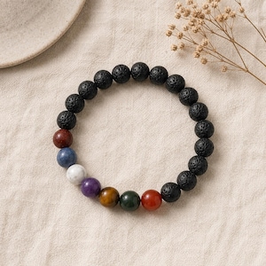Peut inclure: Un bracelet circulaire composé de perles en pierre de lave noire poreuse alternant avec une série de perles en pierres précieuses lisses et multicolores dans des tons de rouge, bleu, blanc, violet, marron, vert et orange.