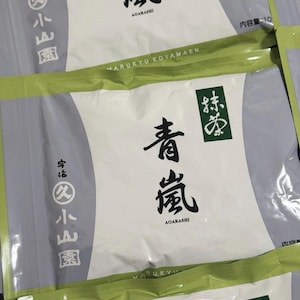Puede incluir: Múltiples bolsas rectangulares blancas y verde claro de té matcha Marukyu Koyamaen Aoarashi. Cada bolsa presenta caligrafía japonesa negra, el texto Aoarashi y el logotipo de Marukyu Koyamaen impresos en el frente con una fuente clara y negrita.