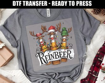 May include: A gray t-shirt with a design of three beer bottles dressed as reindeer with the text "Reinbeer".