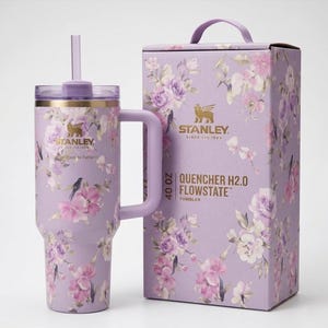 May include: A 40 oz Stanley Quencher H2.0 Flowstate tumbler and matching box. The tumbler and box are lavender with a floral pattern in pink, purple, and white. The tumbler has a handle and straw.