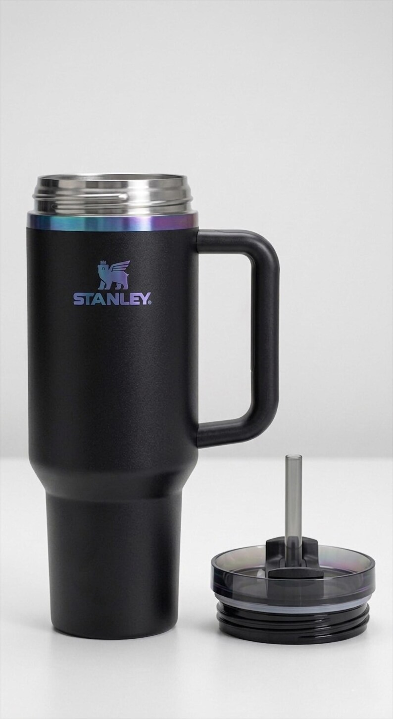 Puede incluir: Vaso t&eacute;rmico negro con asa y tapa. El vaso tiene un borde de acero inoxidable con un acabado iridiscente arco&iacute;ris. El logotipo de Stanley est&aacute; impreso en la parte delantera. La tapa y la pajita est&aacute;n separadas.