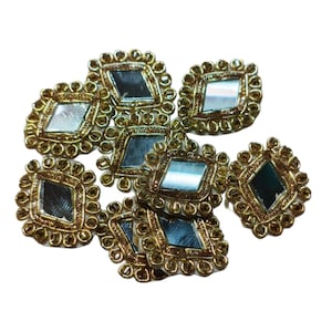 May include: A collection of decorative embellishments with a gold-coloured, ornate border. Each embellishment features a mirrored, diamond-shaped centre. The embellishments are arranged on a white background.