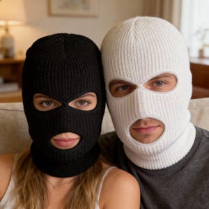May include: A black and a white knitted balaclava, each covering the head and face with openings for the eyes and mouth. The black balaclava is worn by a person on the left, and the white one is worn by a person on the right.