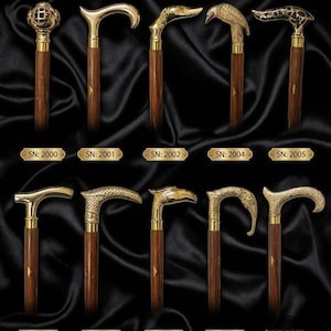 May include: A collection of ten walking sticks with dark brown wooden shafts and ornate brass handles. The handles feature various designs including a diver helmet, animal heads, and textured patterns. Each stick is labelled with a serial number.