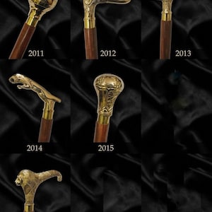May include: A collection of seven walking sticks with dark wooden shafts and polished brass handles. The handles feature distinct designs including a globe, a duck head, an ornate curved grip, a leaping panther, a textured knob, and a lion head.