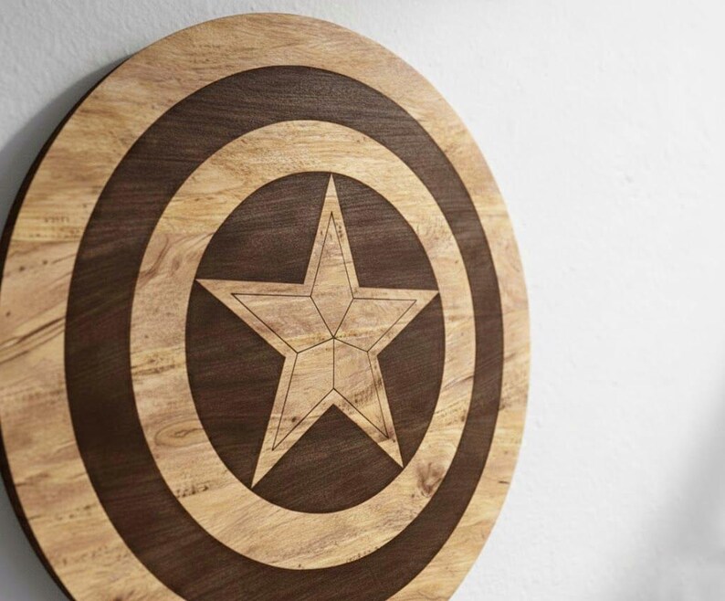 May include: A wooden Captain America shield with a star design. The shield is round with concentric circles in light and dark brown wood. A five-pointed star is in the center, also in light brown wood.