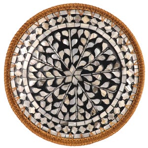 May include: Round decorative tray with a woven brown border. The center features a black background with a mosaic design of white and iridescent shell pieces arranged in a floral pattern. A unique home decor item.