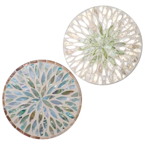 Puede incluir: Dos posavasos redondos decorativos con diseños de mosaico. Uno presenta un patrón floral azul y verde, mientras que el otro tiene un diseño floral verde y blanco. Ambos posavasos tienen un aspecto nacarado, de unos 10 cm de diámetro.
