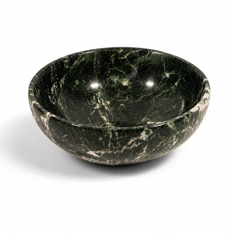 May include: A round bowl crafted from dark green marble featuring prominent white veining throughout the stone surface. The bowl has a smooth, polished finish with a deep interior basin and a curved exterior wall, showcasing the natural patterns.