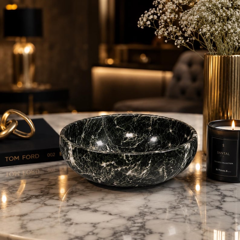 May include: A round, deep bowl crafted from dark green marble with prominent white veining throughout its surface. The bowl features a smooth, polished finish and a curved, basin-like shape, showcasing the natural stone patterns and textures.