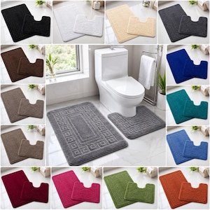 May include: A two-piece bathroom rug set comprising a rectangular mat and a U-shaped contour mat. Both items feature a textured Greek key border design. The set is available in a range of solid colours including black, white, beige, grey, blue, and red.