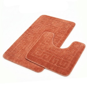 Könnte beinhalten: Ein Set aus drei terrakottafarbenen Badezimmerteppichen. Der rechteckige Teppich und der konturierte Toilettensitzteppich weisen ein sich wiederholendes geometrisches Muster auf. Die Teppiche bestehen aus einem weichen, plüschigen Material.