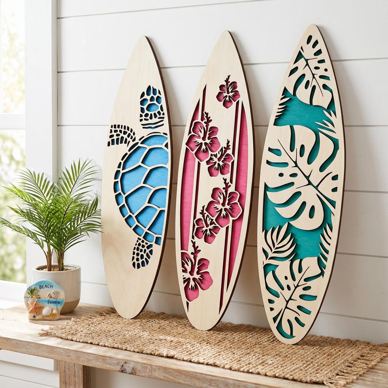 May include: Three wooden surfboards with laser-cut designs. One features a turtle, another hibiscus flowers, and the third tropical leaves. Each board has a light wood finish with colorful accents of blue, pink, and teal.
