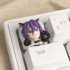 May include: A custom keycap featuring a purple-haired anime-style character with cat ears and green eyes. The keycap is on a white keyboard, with the "TAB", "1", "!", and "F1" keys visible. The character is wearing black gloves and a white shirt.