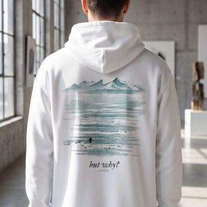 Puede incluir: Sudadera con capucha blanca con un diseño de paisaje en la espalda. El diseño presenta una cordillera, agua y una pequeña figura. El texto "but why?" y la marca "QUENOVA" están impresos debajo.