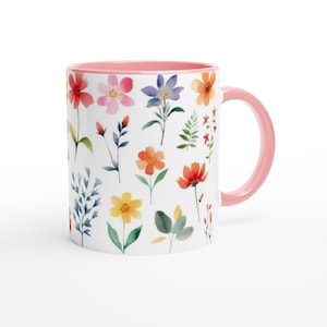 Puede incluir: Taza de cerámica blanca con interior y asa rosas. La taza está decorada con un estampado floral de acuarela con varias flores coloridas y hojas verdes. Las flores incluyen flores rojas, rosas, naranjas, amarillas y azules.