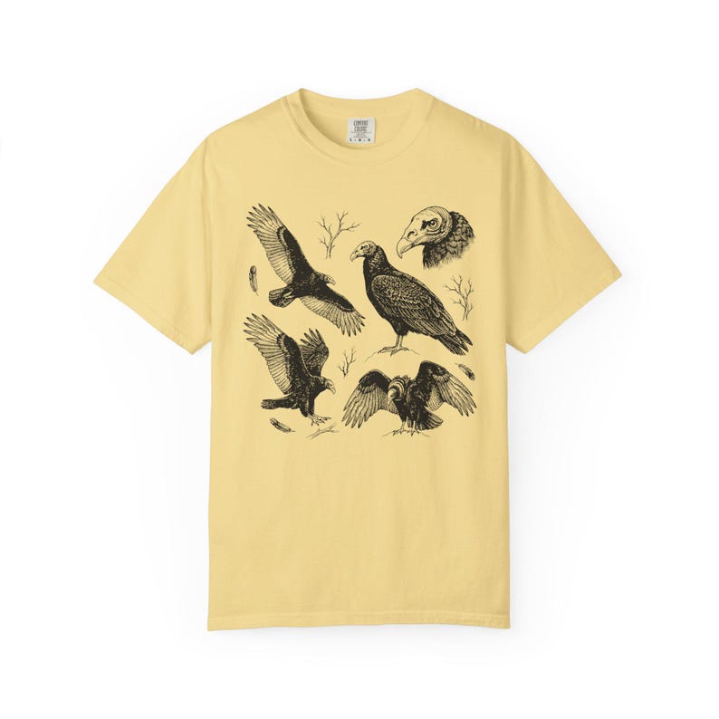 Butter yellow Comfort Colors t-shirt with a vintage engraved illustration of five vultures including one soaring with wings outstretched, one standing with wings half-spread, a close-up portrait showing bare head and hooked beak, one landing with wings fanned, and one spreading wings low in a dominance display, surrounded by bare winter branches and scattered feathers in an antique wildlife field guide etching style.