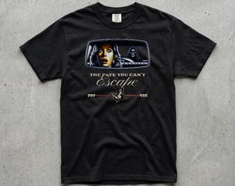 May include: Black t-shirt featuring a graphic of a car's rearview mirror with a terrified woman and a grim reaper. The text "THE FATE YOU CAN'T ESCAPE" is below the mirror, with additional text and a butterfly graphic.