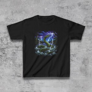 May include: Black t-shirt featuring a graphic of a sea serpent in water with lightning bolts and a dark forest background. The serpent is green and yellow, with a long, serpentine body. The lightning is white and blue.