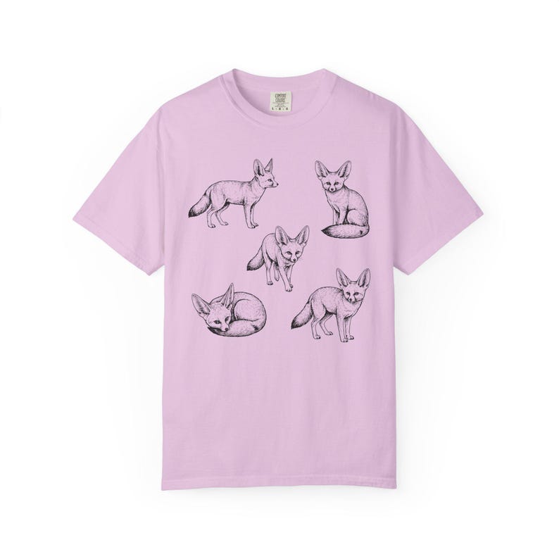 Orchid purple graphic t-shirt featuring a vintage engraved style illustration of multiple fennec foxes arranged in different poses. The foxes are shown sitting, walking, and curled up, with detailed linework creating a naturalist wildlife illustration and desert animal aesthetic.