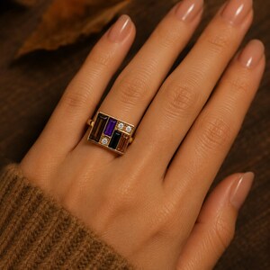 Puede incluir: Un anillo de oro con un dise&ntilde;o rectangular con piedras preciosas de varios colores. El dise&ntilde;o incluye piedras de corte rectangular en tonos marr&oacute;n, morado y negro, acentuadas con peque&ntilde;as piedras redondas y claras. El anillo est&aacute; engarzado en una banda de oro.