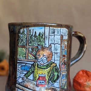 Peut inclure: Mug en céramique fait à la main avec une illustration d'un renard portant un tablier jaune et une chemise verte, devant une fenêtre. La tasse est marron avec une anse foncée, d'une capacité d'environ 350 ml.
