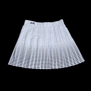May include: White pleated skirt with a blue and black striped pattern. The skirt has the brand name "ellesse" printed in blue at the waistband. The skirt is designed with a gradient effect, transitioning from solid stripes to open spaces.