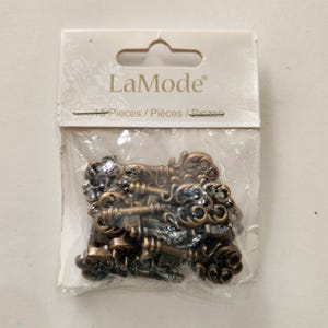May include: A package of 15 antique-style keys in a clear plastic bag. The keys are bronze-colored with ornate designs. The package has a white label with the brand name "LaMode" and the text "15 Pieces / Pièces / Piezas".