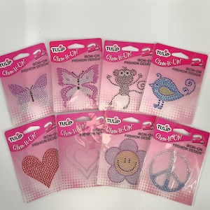 May include: A collection of Tulip Glam-It-Up! iron-on fashion designs. Designs include butterflies, a monkey, a bird, a heart, a flower with a smiley face, and a peace sign. Each design is made of rhinestones.
