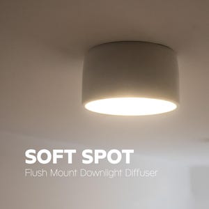 Könnte beinhalten: Ein zylindrischer, weißer, bündig montierter Downlight-Diffusor, der ein warmes Licht abgibt und an der Decke installiert ist. Der Text SOFT SPOT Flush Mount Downlight Diffuser ist unten links im Bild zu sehen und gibt den Produktnamen an.