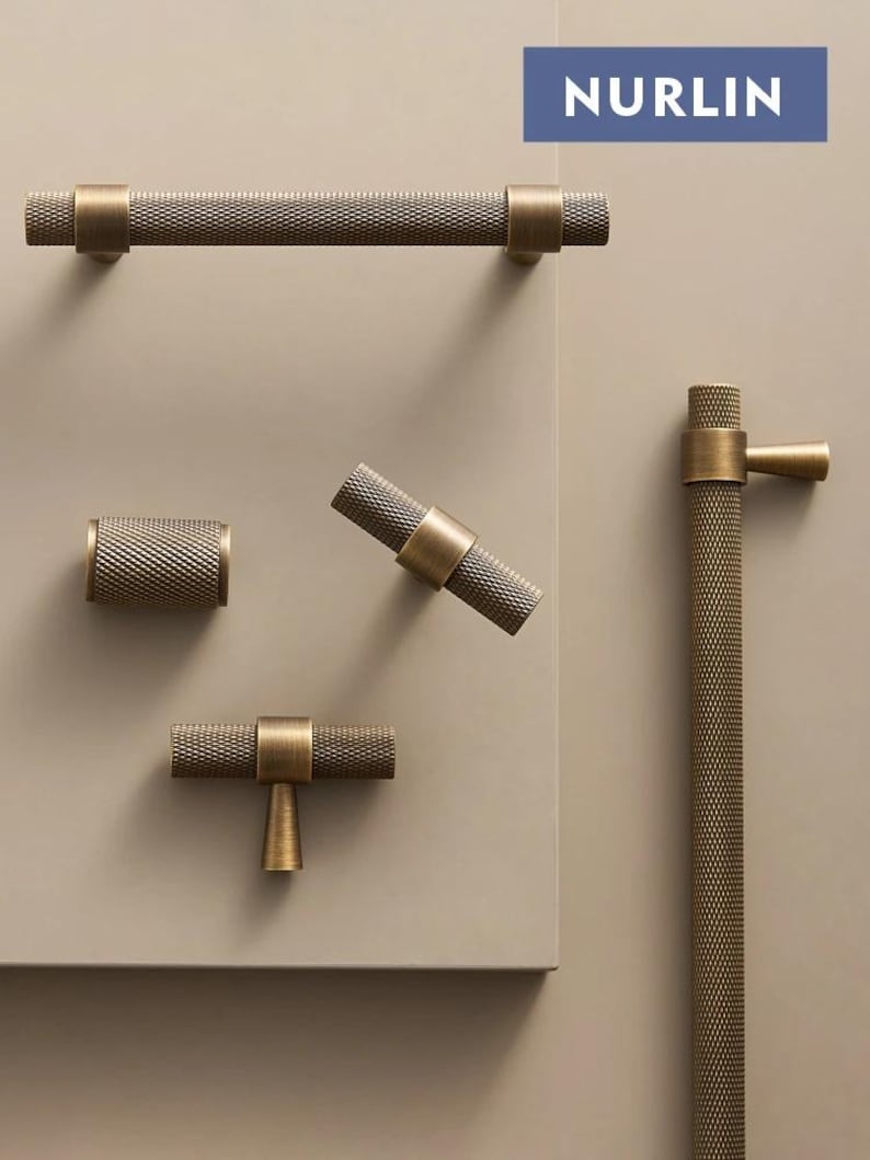 May include: A collection of bronze-toned cabinet hardware, including a long bar pull, a cylindrical knob, a T-shaped pull, and a vertical handle. The hardware features a textured, cross-hatched pattern and is set against a neutral background. The word "NURLIN" is displayed in a blue rectangle.
