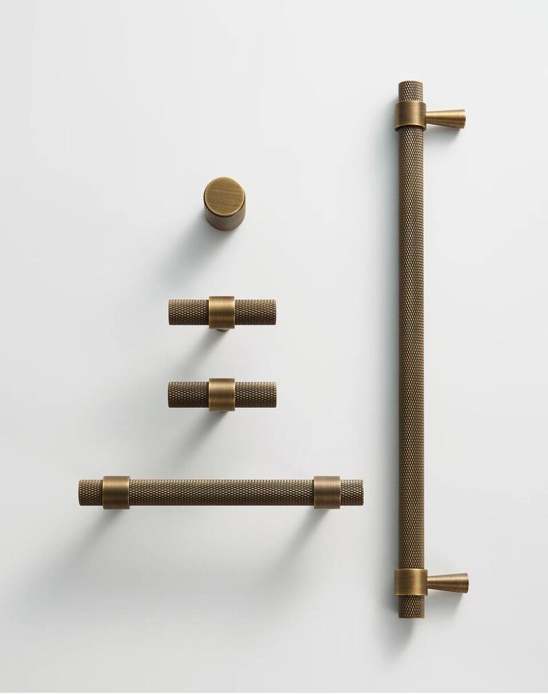 May include: A collection of antique brass cabinet hardware, including a knob, two T-bar pulls, a long bar pull, and a large handle. The hardware features a textured, dotted pattern and is designed for furniture or cabinetry.