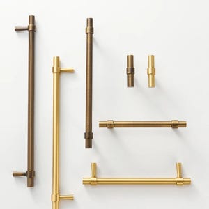 Könnte beinhalten: Eine weiße Keramik-Tasse mit schwarzem Henkel und dem Text "But First, Coffee" in schwarzer, fetter Schrift. Die Tasse steht auf einer Holzoberfläche. Die Tasse ist etwa 10 cm hoch.