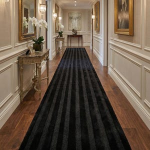 May include: A long, black and gray striped runner rug in a hallway with hardwood floors. The rug is the focal point, with vertical stripes adding visual interest. The hallway features decorative wall paneling, artwork, and lighting fixtures.