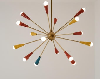 May include: A retro-style chandelier with a brass finish and multiple arms radiating outwards. The arms feature red, yellow, and blue cone-shaped accents with white light bulbs. The light fixture is suspended from the ceiling.