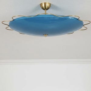 May include: A vintage ceiling light fixture with a blue glass shade and brass accents. The shade is a rounded, scalloped shape. The fixture is mounted on a white ceiling.