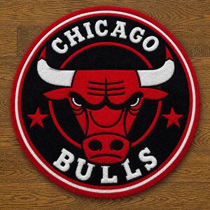 May include: Circular rug featuring the Chicago Bulls logo. The design includes a red bull head with white horns, set against a black background, and surrounded by a red and white border. The words "CHICAGO" and "BULLS" are in white.